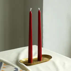 Détail de bougies coniques rouges sur plateau en laiton rétro, idéal pour déco de table et ambiance.
