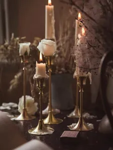 Vintage brass candlestick holders with white taper candles and romantic rose decor for home atmosphere.