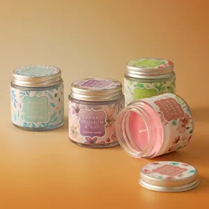 Glass jar scented candle detail showing floral label, metallic lid and colorful wax inside.