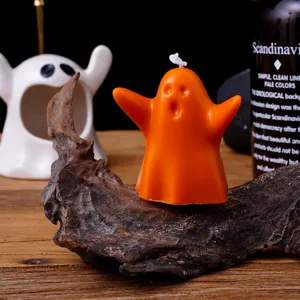 Gros plan détaillé de la jolie bougie parfumée en forme de fantôme orange sur décor en bois.