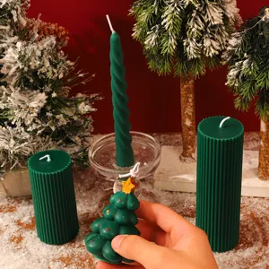 Vue de détail des bougies parfumées de Noël vertes en forme de sapin et pilier sous la neige.