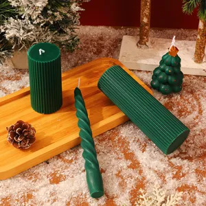 Gros plan de bougies parfumées de Noël vert foncé sur un plateau en bois avec de la neige.