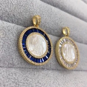Detailed close-up of round gold-tone pendant with white mother-of-pearl and blue cubic zirconia.