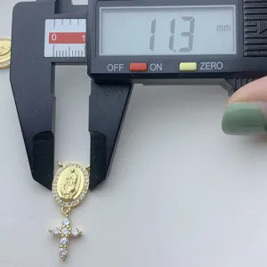 Detailaufnahme des goldenen Zirkon Porträthängers mit Kreuzaccessoire und Messschieber.