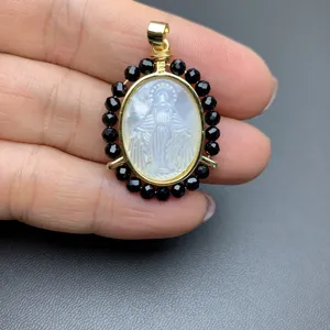 Mother of pearl carved portrait pendant with black beaded halo and 925 bail detail.