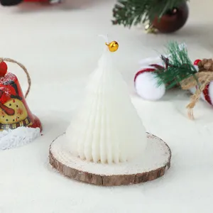 Close-up detail of white Christmas tree scented candle with wood slice base and holiday props.
