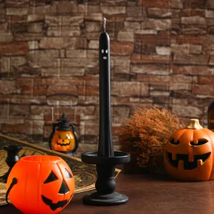 Detailed view of Halloween ghost candle with black holder and decorative pumpkin props.