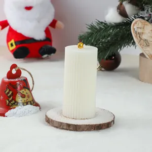 White ribbed pillar candle detail on wood slice base with festive Christmas decor scene.