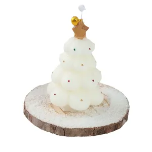 Christmas tree scented candle with wooden base and bell ornament for holiday decoration.