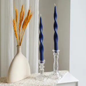 Detailed view of blue twisted scented taper candle in glass holder with dried wheat decor.