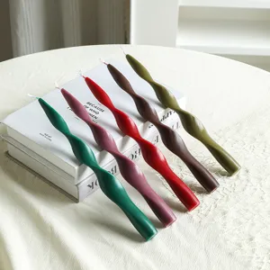 Close-up detail of colorful spiral taper candles arranged on decorative books tabletop.