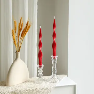 Detail view of red twisted long soy wax candles in clear glass holders with wheat deco.
