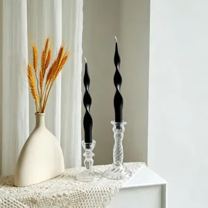 Detail shot of black twisted scented candles in glass holders with dry wheat decor.