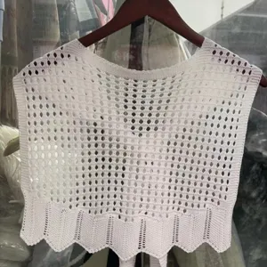 Close-up view of a white knitted hollow shawl, showing fine crochet texture and wavy hem.