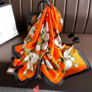 Orange silk scarf detail showing elegant white floral pattern and black border drape.