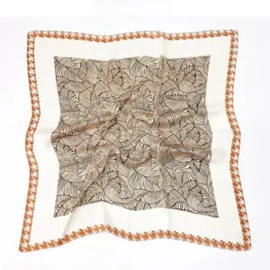 Close-up detail of vintage silk scarf featuring elegant leaf pattern and classic houndstooth border.