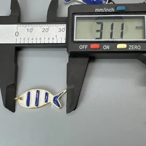 Detailaufnahme eines Emaillierter Fisch Anhängers mit Messschieber für DIY Schmuckherstellung.