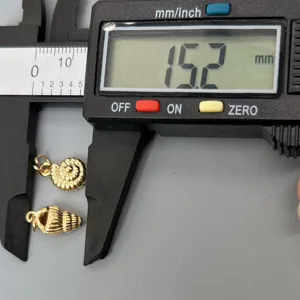 Detailansicht der goldenen Muschelanhänger mit Messschieber, ideal für DIY Strand Schmuckdesign.