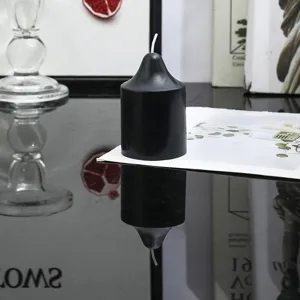Gros plan de la bougie parfumée cylindrique noire pointue, détail sur table réfléchissante.