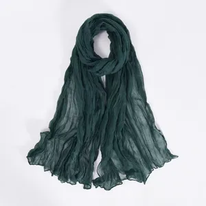 Detailed view of a dark green crinkled plain bali yarn scarf, soft lightweight shawl hijab.
