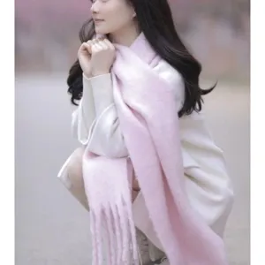 Gros plan d'une écharpe d'hiver rose douce à franges, accessoire douillet style mohair.