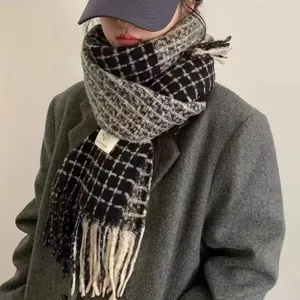 Écharpe à carreaux femme hiver, motif classique noir et gris avec franges élégantes.