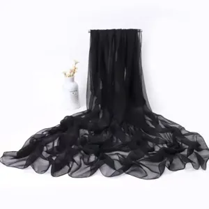 Detail view of a black lightweight solid color chiffon scarf, elegant draped style for women.