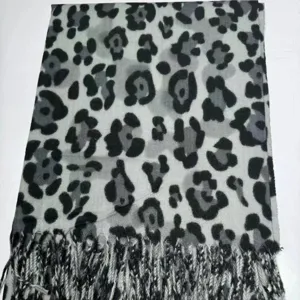 Vue détaillée de l'écharpe à motif léopard noir et gris avec franges, douce et chaude.