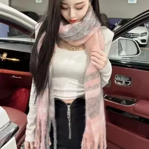 Gros plan détail de l'écharpe à carreaux en mohair duveteux rose et gris, texture douce.