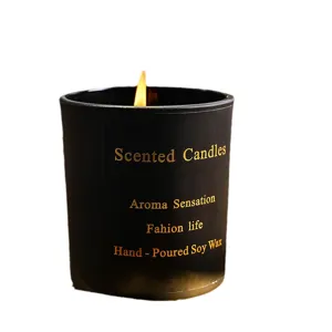 Black scented candle in glass jar with burning flame, handmade soy wax home decor item