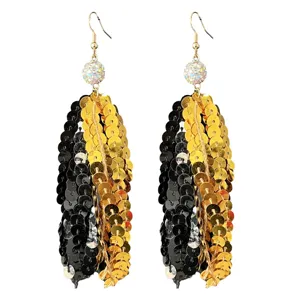 Gros plan de boucles d'oreilles longues à sequins avec boules de strass pour la fête.