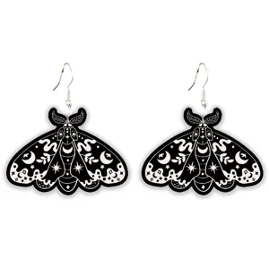 Gothic black and white moth earrings close-up with celestial moon and star pattern details.