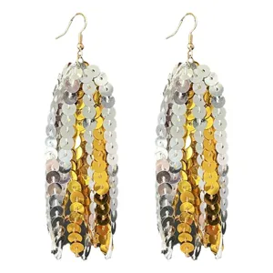 Gros plan de boucles d'oreilles à franges de sequins étincelantes, disques dorés et argentés.