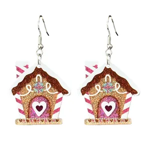 Nahaufnahme von Weihnachts-Lebkuchenhaus-Glitzer-Ohrringen, süßer Festtags-Modeschmuck für Frauen.