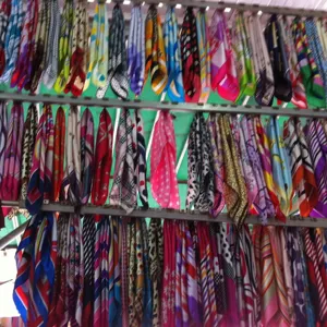 Assorted colorful printed silk scarves hanging on display rack showcasing various patterns.
