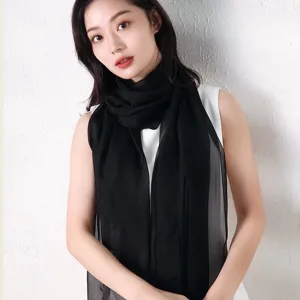 Vue détaillée d'un foulard long et léger en mousseline noire unie sur un modèle.