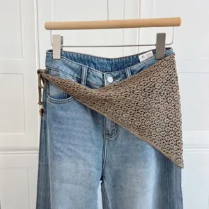 Vue détaillée d'un foulard triangulaire au crochet fait main avec un pantalon en jean.