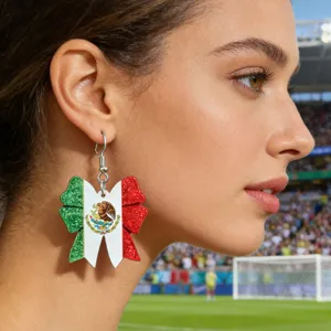 Detailed close-up shot of glittery Mexico flag bow earrings worn by a model in a stadium.