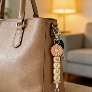 Detailed view of wooden bead MAMA sunflower keychain gracefully hanging on a brown leather bag.