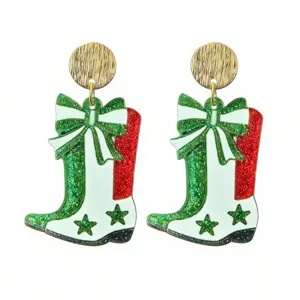 Close-up of glittery cowboy boot earrings with bow detail, festive green and red finish.