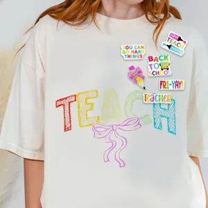 Detail shot of teacher themed graphic t-shirt featuring colorful lettering and cute sparkling pin badges.