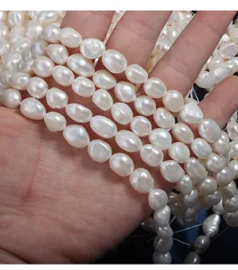 Close-up detail of natural freshwater baroque white pearls, drilled bead strands for DIY jewelry making.