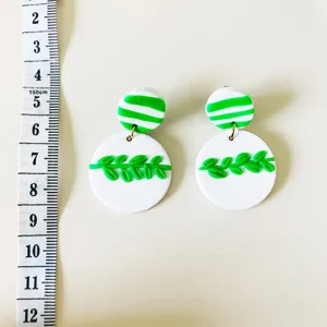 Handgemachte Fimo Ohrringe mit gruenen Blaettern und Streifen im Detail mit Massband.