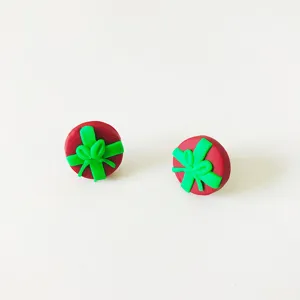 Nahaufnahme der handgefertigten Fimo-Weihnachtsgeschenkbox-Ohrstecker mit grüner Schleife.