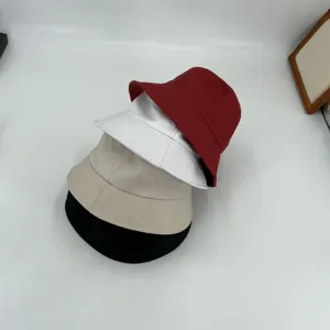 Detailed view of multi-color stacked pure cotton bucket hats, showing red, white, beige and black.