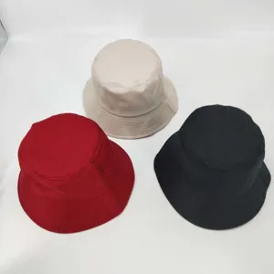 Detail view of solid color bucket hats in red, beige and black, casual sun protection style.