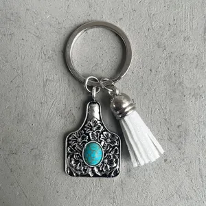 Detailed close-up of the vintage western style cattle tag pendant and white leather tassel.