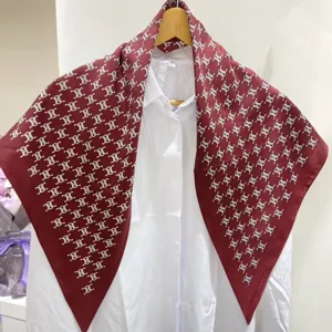 Vista dettagliata del foulard in seta triangolare bordeaux classico, drappeggiato su camicia.