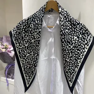Dettaglio della sciarpa triangolare con stampa leopardata in bianco e nero su camicia.