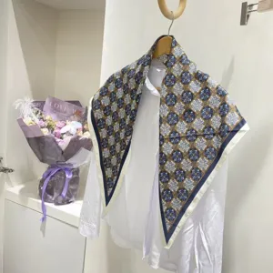 Elegante foulard in seta geometrico blu e bianco drappeggiato su una camicia bianca donna.